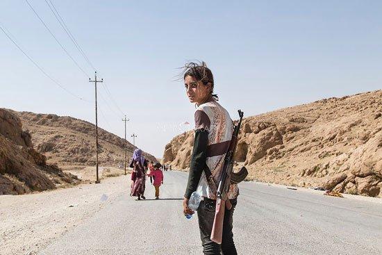 الصورة الثالثة : لفتاة أيزيدية تحمل رشاشاً آلياً وتنظر بعينين حادتين تشهدان على فظائع قام بها تنظيم داعش، وتحمل السلاح فى تلك السن الصغيرة لحمايتها وحماية أهلها من أى هجوم